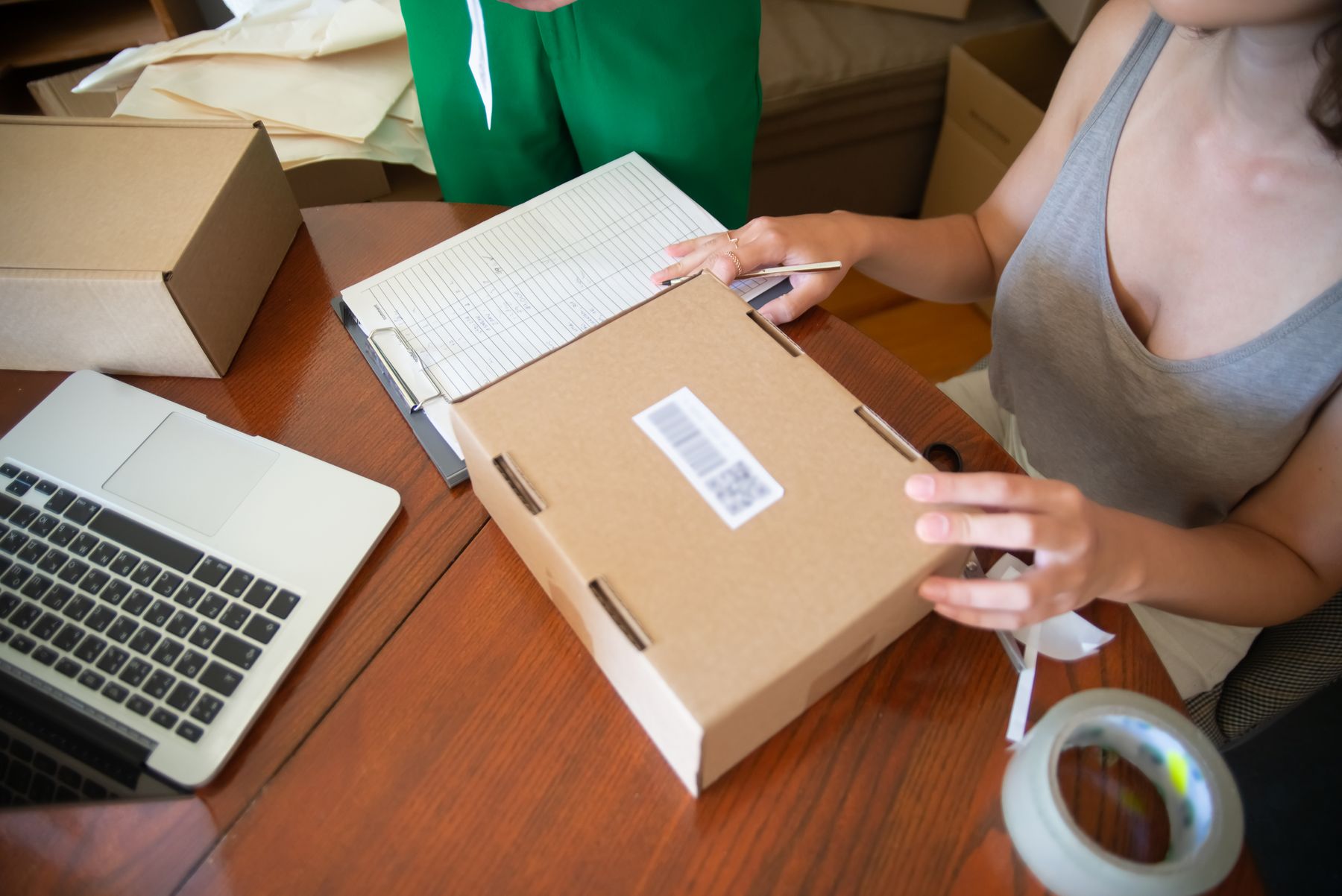 Two people packing orders beside a laptop in a small retail back office.