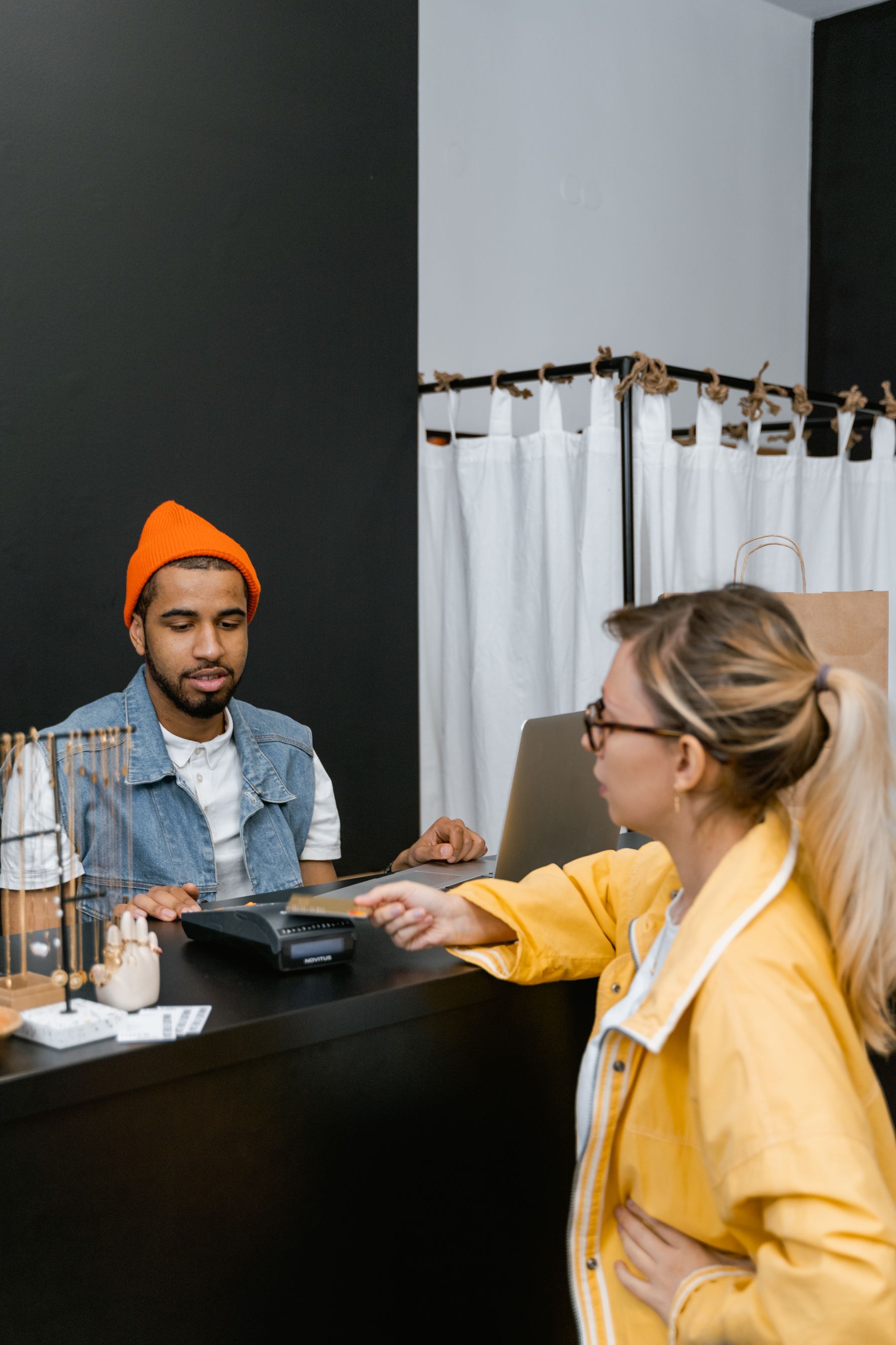 A customer paying by card at a shop counter while the assistant rings up the sale.