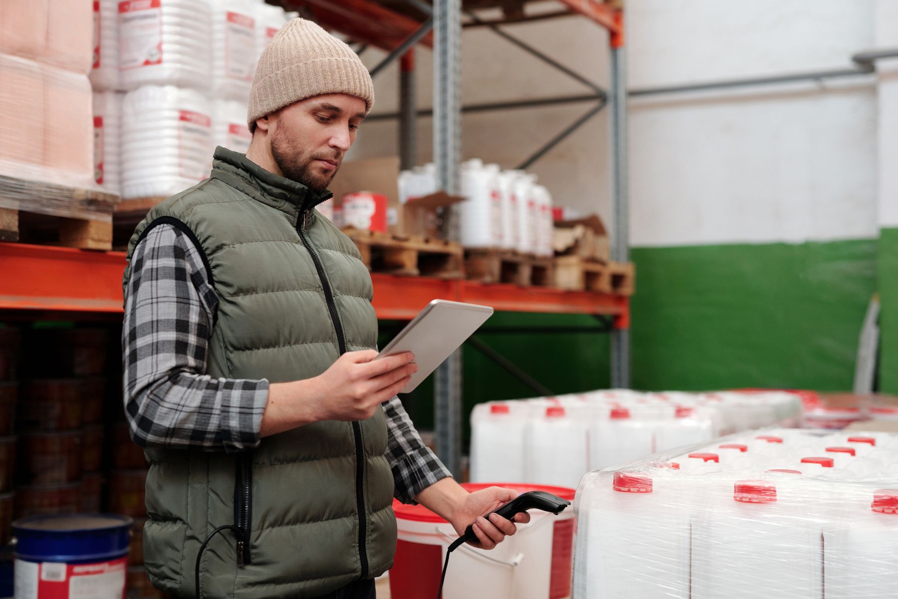 A shop worker checking stock on a tablet with a handheld barcode scanner.