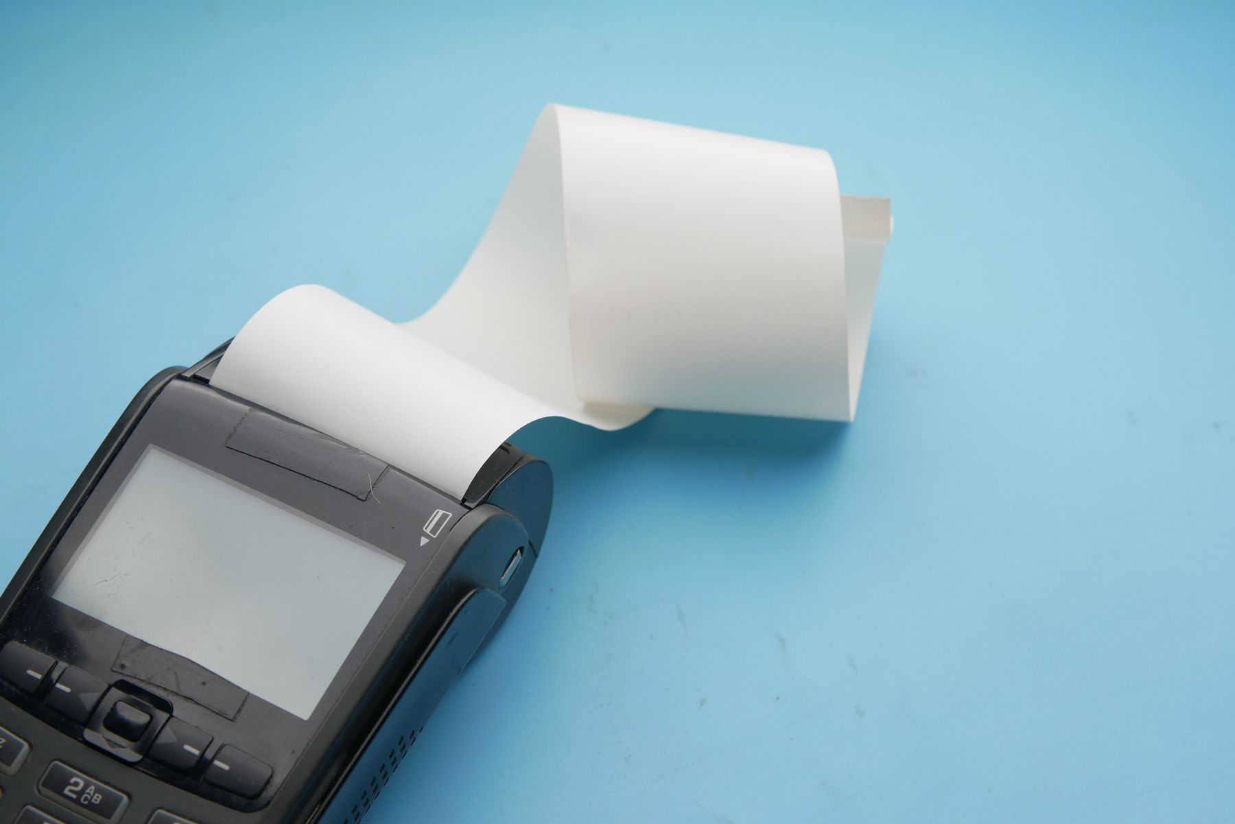 A card terminal with a long thermal receipt curling out of it.
